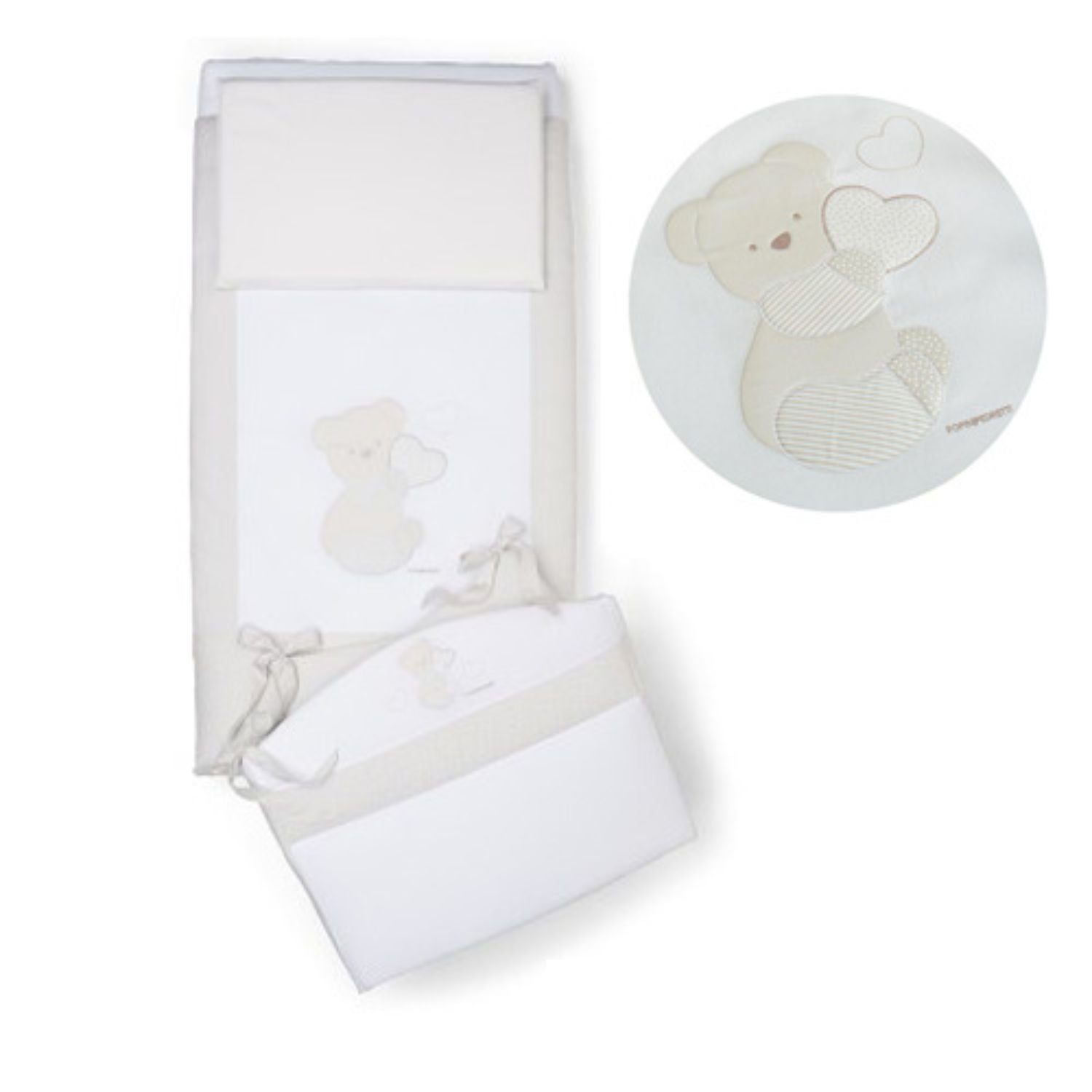 Cream-colored baby crib bedding set featuring embroidered teddy bear holding a heart. 
