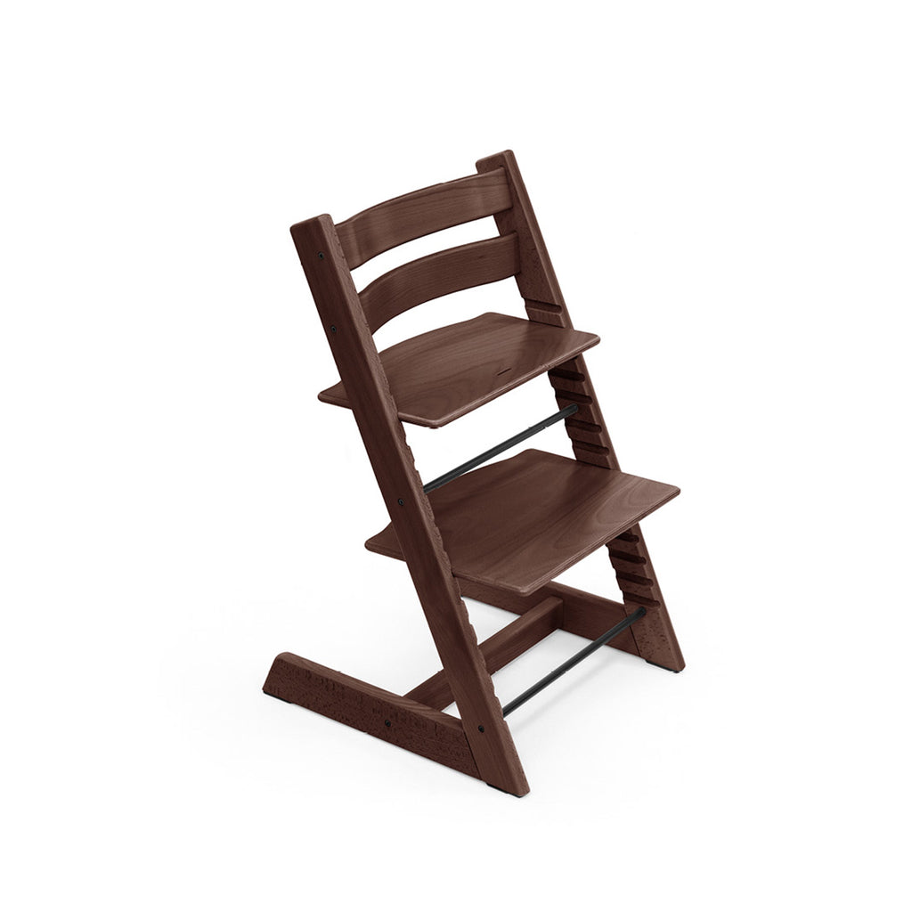 Dark brown wooden high chair with adjustable seat and footrest stands against a white background. 
