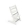 White adjustable wooden high chair with black footrest on white background. 
