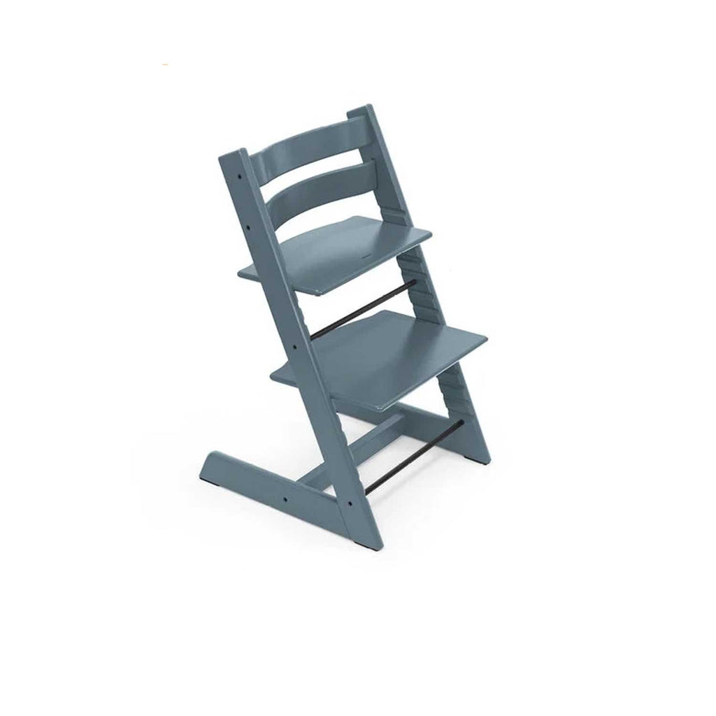 A slate blue adjustable wooden high chair sits at an angle, ready for mealtime. 
